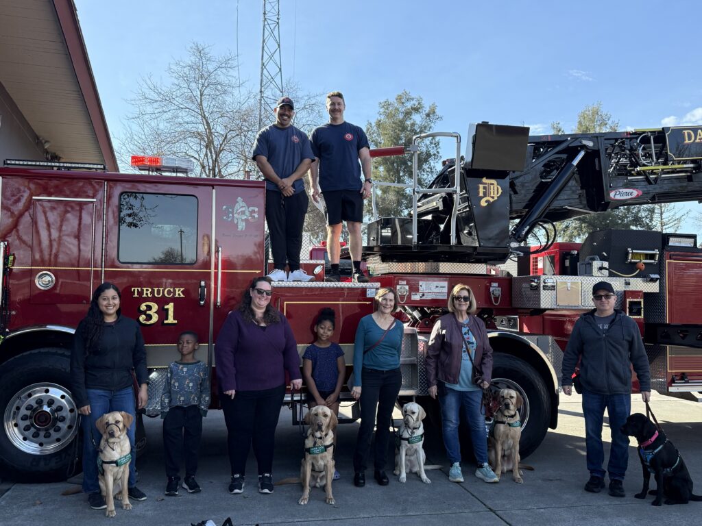 Puppies and raisers in front of a fire engine